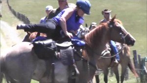Notice the rider holds both the saddle horn and reins with the right hand.